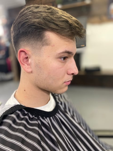 Young man with a faded undercut hairstyle in profile, wearing a striped black and white shirt